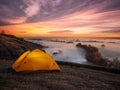 Orange illuminated from inside tent above river at sunset