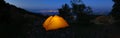 Orange illuminated inside tent on hill above city lights at night Royalty Free Stock Photo