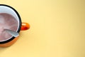 Orange iron cup with cocoa with spoon on light background