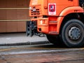 Orange irrigation sweepers truck stand on the tram tracks. Moscow coat of arms. Cityscape