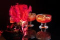 Orange jello on a beautiful bowl with fruit pieces inside. Black background, decorated with pink feathers.