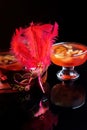 Orange jello on a beautiful bowl with fruit pieces inside. Black background, decorated with pink feathers.