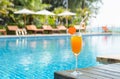 Orange juice glass on wooden table with swimming pool view background Royalty Free Stock Photo