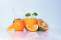 Orange juice drinks with straw and mint leaf on a white reflective background and plate. Royalty Free Stock Photo