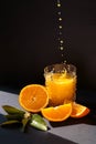 Orange juice drops into glass with orange juice, sliced oranges with blossom