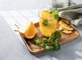 Orange juice with fresh fruits, mint and ice on a light background with shadow and napkin. Healthy freshly squeezed citrus detox