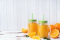 Orange juice in glass jars and fresh oranges on a white wooden rustic background Royalty Free Stock Photo