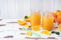 Orange juice in glass jars and fresh oranges on a white wooden rustic background Royalty Free Stock Photo