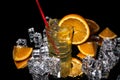 Orange juice in a glass with sliced orange and ice cubes, and with reflection on shiny black background Royalty Free Stock Photo