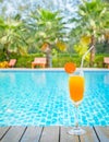 Orange juice glass on wooden table with swimming pool view background Royalty Free Stock Photo