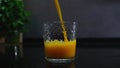 orange juice is poured into glass on gray background in the kitchen