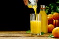 orange juice pouring into glass on dark background. fresh organic orange juice Royalty Free Stock Photo