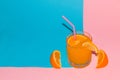 orange juice with slice orange in the juice and next to the glass and straw on a pink-blue background and copy space Royalty Free Stock Photo