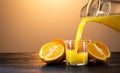 Orange juice splashing to the glass. ext to it on the table are sliced and whole oranges. the setting sun. orange Royalty Free Stock Photo