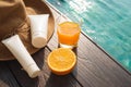 Orange juice, straw hat, sunblock and sunglasses by poolside Royalty Free Stock Photo