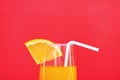 Orange juice summer glass with piece orange fruit on red background