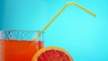 Orange juice in a transparent glass with a straw. Chilled lemonade on a blue background Royalty Free Stock Photo