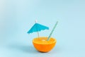 Orange juice with tubule and umbrella. Orange cut in half on pastel blue background Royalty Free Stock Photo