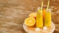 Orange juice on a wooden tray. Sliced orange and ice cubes