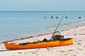 Orange kayak, fitted for fishing, resting on sandy, tropical beach Royalty Free Stock Photo