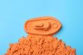 Orange kinetic sand on light blue background, flat lay Royalty Free Stock Photo