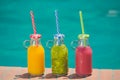 Fresh colorful fruit juice smoothies at the edge of swimming poo Royalty Free Stock Photo