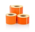 Orange label roll isolated on white background with shadow reflection. Color reel of labels for printers.