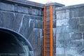 An orange ladder fixed in a water canal at the arched stone bridge in Odense. Denmark