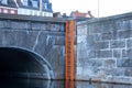 An orange ladder fixed in a water canal at the arched stone bridge in Odense. Denmark