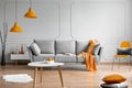 Orange lamp above grey scandinavian sofa