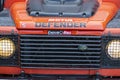 Orange Land Rover Defender. Front side of offroad vehicle. 4x4 tour.