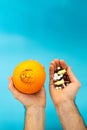 Orange with a large navel  pills in hands on a blue background. hemorrhoid drug treatment concept Royalty Free Stock Photo