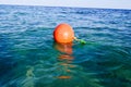 Orange large round plastic rescue buoy floats in the blue salt sea for safety. Royalty Free Stock Photo