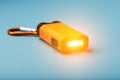 Orange led Flashlight with a carabiner on a blue background. LED lights in flight Royalty Free Stock Photo