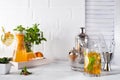 Orange lemonade in the decanter on a wooden tray, cocktail glass with ice, mint and ginger and Cocktail shaker with a Royalty Free Stock Photo