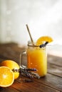 Orange lemonade in a mug on a wooden table flooded with light from the window Royalty Free Stock Photo