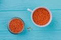 Orange lentils in ceramic and glass cups.