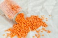 Orange lentils in a glass jar on a linen tablecloth.