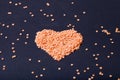 Orange lentils in a heart shape on a black background. Selective Royalty Free Stock Photo