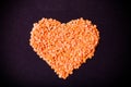 Orange lentils in a heart shape on a black background. Toned Royalty Free Stock Photo