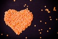 Orange lentils in a heart shape on a black background. Toned Royalty Free Stock Photo