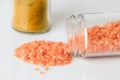 Orange lentils scattered from glass jar