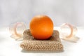 The orange lies on a mesh washcloth made from natural fibers, and next to it are vacuum banks.