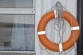 Orange life buoy hanging next to a window with a reflection of the sea. Royalty Free Stock Photo