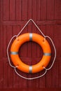 Orange life buoy hanging on red wooden wall Royalty Free Stock Photo