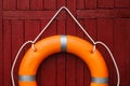 Orange life buoy hanging on red wooden wall Royalty Free Stock Photo