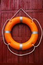 Orange life buoy hanging on red wooden wall Royalty Free Stock Photo