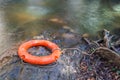 Orange life buoy over the clear water of natural stream. Royalty Free Stock Photo