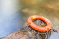 Orange life buoy over the clear water of natural stream. Royalty Free Stock Photo