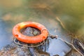 Orange life buoy over the clear water of natural stream. Royalty Free Stock Photo